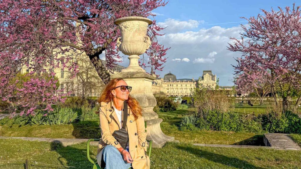 Dame i park i Paris omgitt av tr&aelig;r med rosa kirseb&aelig;rblomster