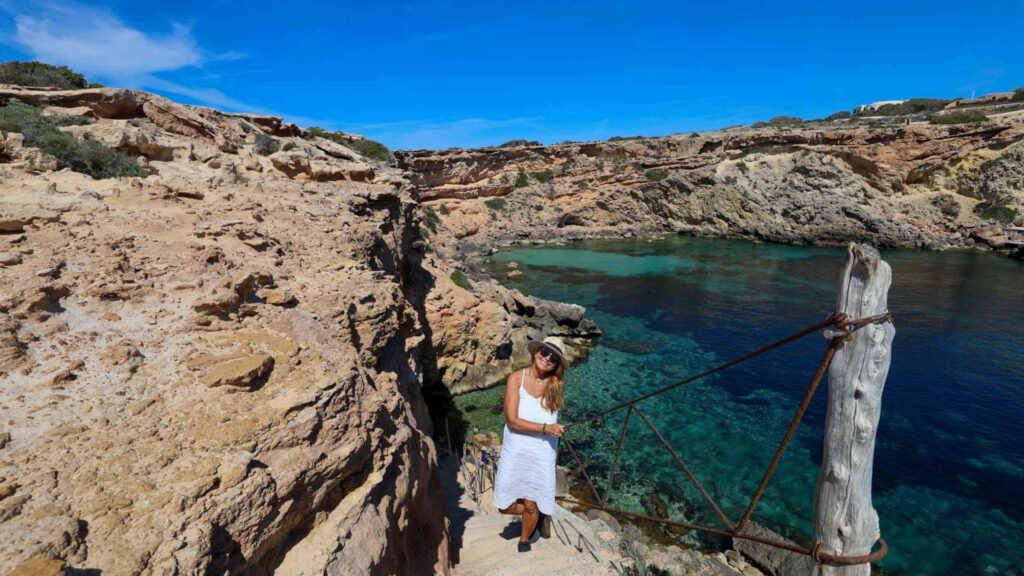 Trapp ned til Cala Comte Cave på Ibiza omgitt av klipper og krystallklart vann ved Platges de Comte på sørvestkysten av øya.