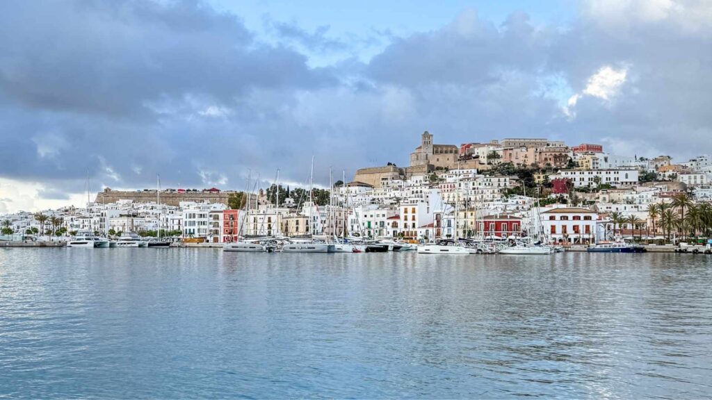 Utsikt mot UNESCO-byen Dalt Vila og havnen i Ibiza by med båter og hvitkalkede hus langs vannet.