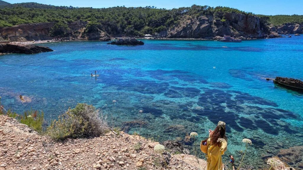 Utsikt over bukten ved Sant Miquel de Balansat på nordkysten av Ibiza med krystallklart turkist hav, klipper og små viker omgitt av furuskog.