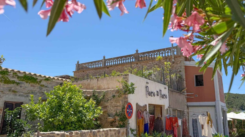 Boutiquebutikk og bohemsk atmosfære i landsbyen Sant Joan de Labritja nord på Ibiza omgitt av blomster og tradisjonell ibizisk arkitektur.