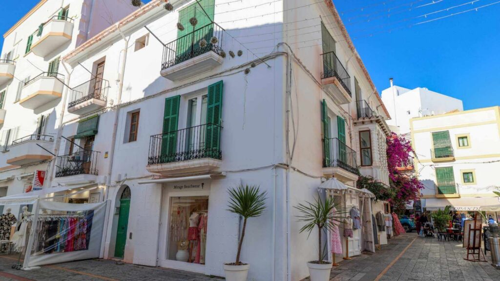 Små butikker og hvite middelhavshus i en rolig gate i Ibiza by.