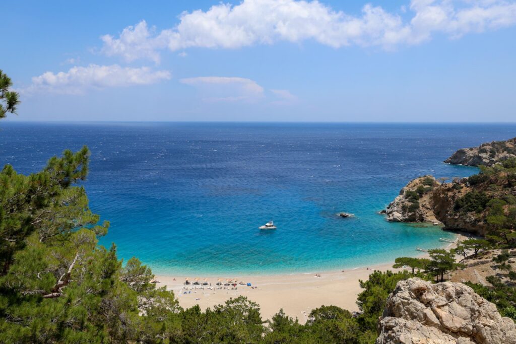 Apella Beach på Karpathos med krystallklart vann, hvit rullesteinstrand og høye klipper – regnet som en av Hellas' vakreste strender.