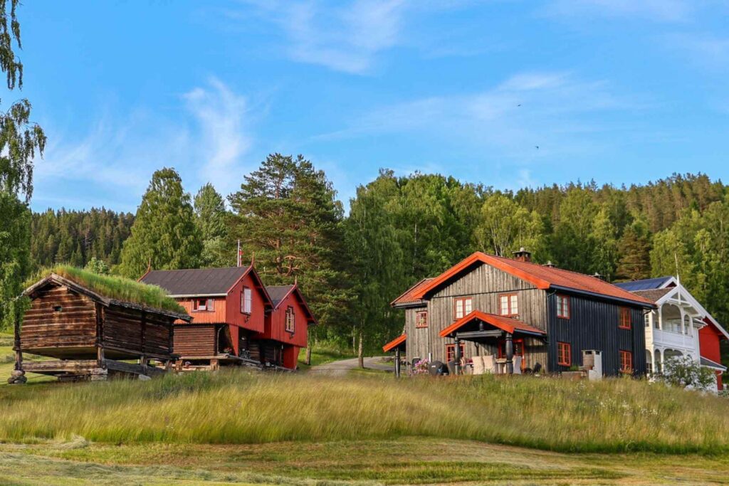 Hovedhuset og de historiske stabburene på Bolkesjø Gaard omgitt av kulturlandskapet i Telemark.