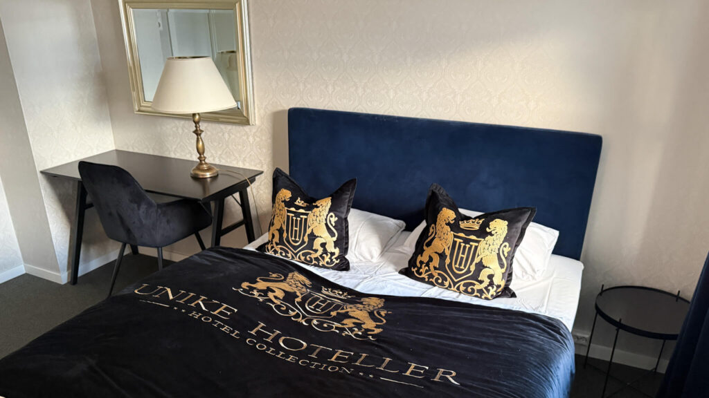 Lyst og komfortabelt dobbeltrom på Brattrein Hotell, Unike Hoteller, med arbeidsplass og dobbeltseng.