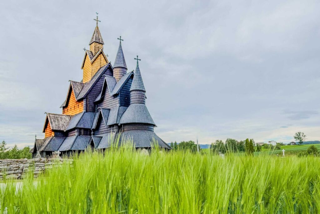 Heddal stavkirke, Norges største stavkirke, omgitt av grønne jorder i Telemark.