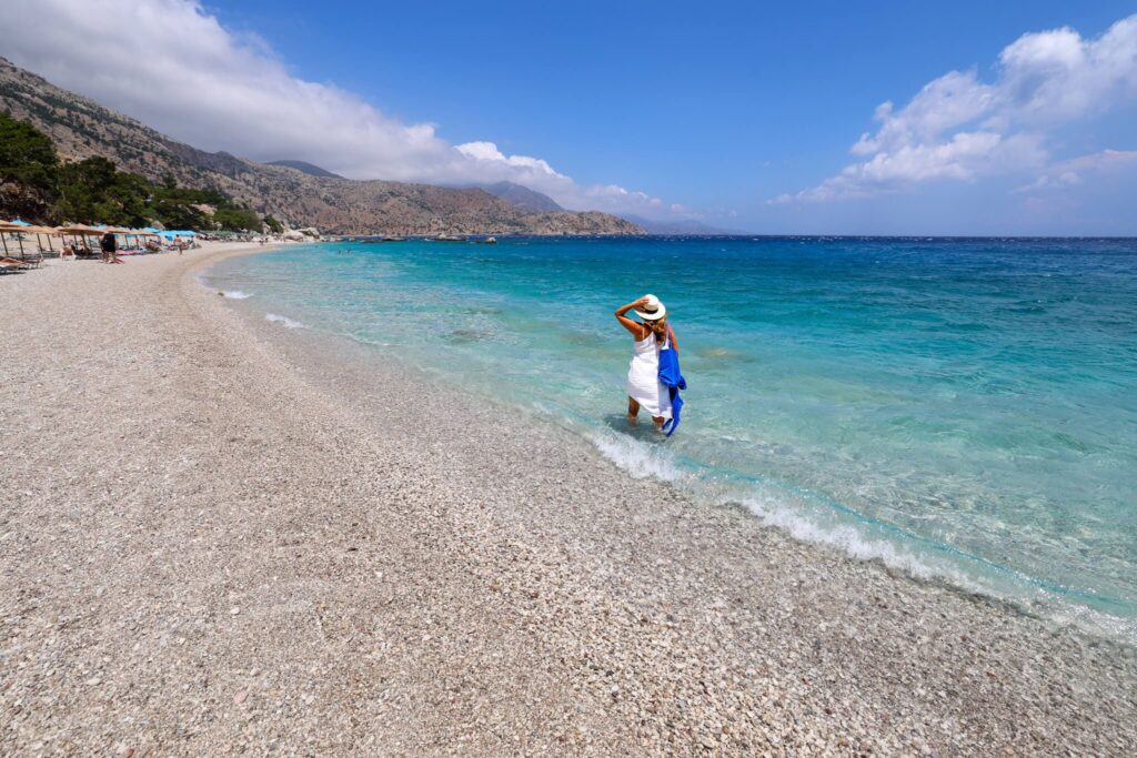 Apella Beach på Karpathos med klart vann og dramatiske fjell i bakgrunnen.
