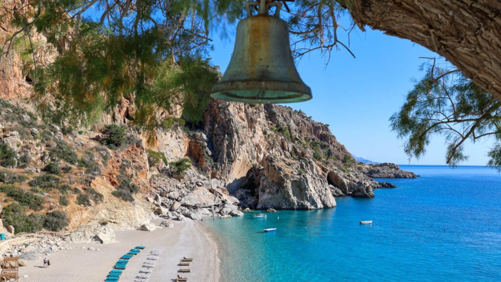 Kyra Panagia Beach på Karpathos med turkis vann, hvit rullesteinstrand og bratte klipper.