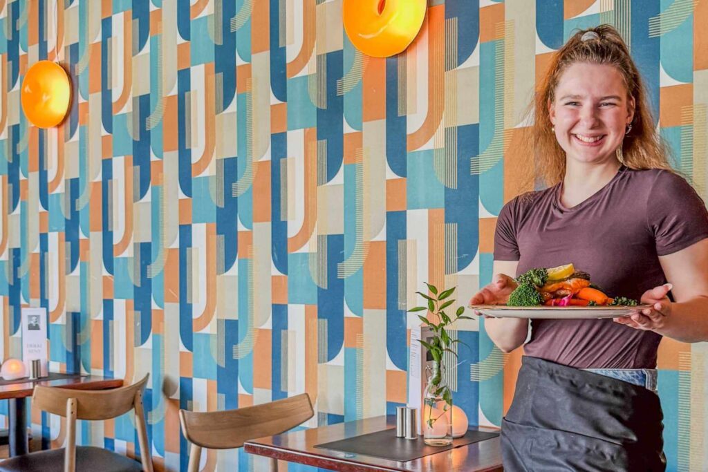 Servitør serverer grillet Telemarksrøye på Restaurant Eyde i Notodden, med fokus på lokale råvarer fra Telemark.