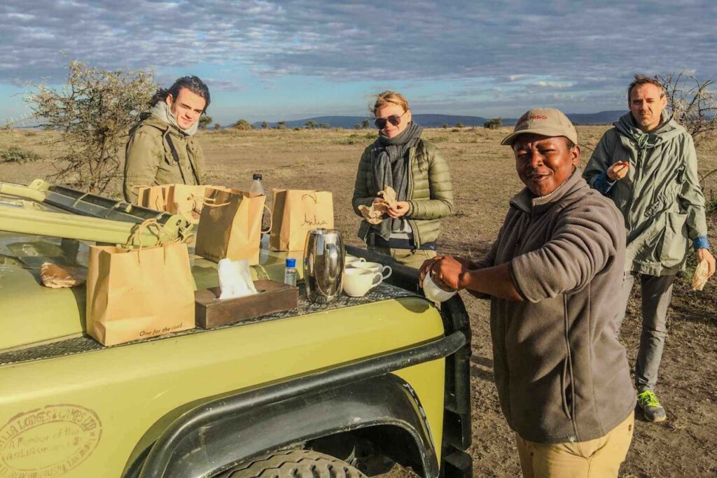 Guiden serverer frokost til familien en tidlig morgen p&aring; safari. 