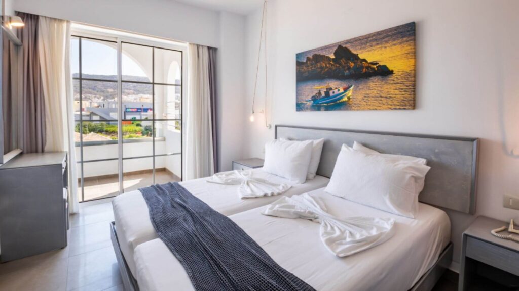 Lyst soverom med dobbeltseng, moderne innredning og balkong.