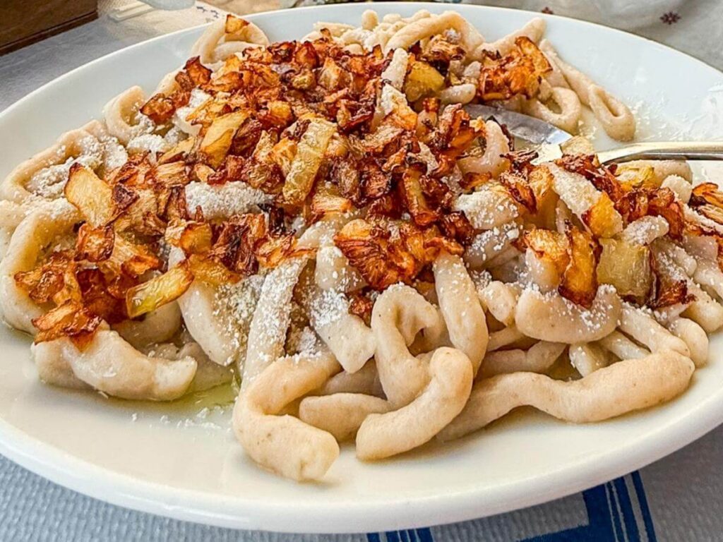 Makarounes, tradisjonell h&aring;ndlaget pasta fra Karpathos, servert med stekt l&oslash;k og revet lokal ost.