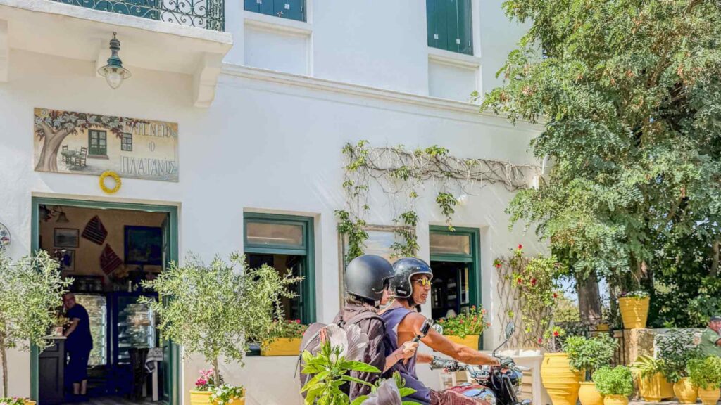 Tradisjonell hvit bygning med gr&oslash;nne vinduskarmer, blomster og motorsykkel p&aring; Kythira.